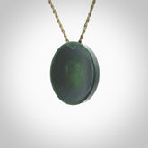This piece is a oval round, cupped disc pendant. It was carved for us by Ric Moor from a lovely dark green piece of New Zealand jade. It is suspended on a khaki coloured braided cord that is length adjustable.